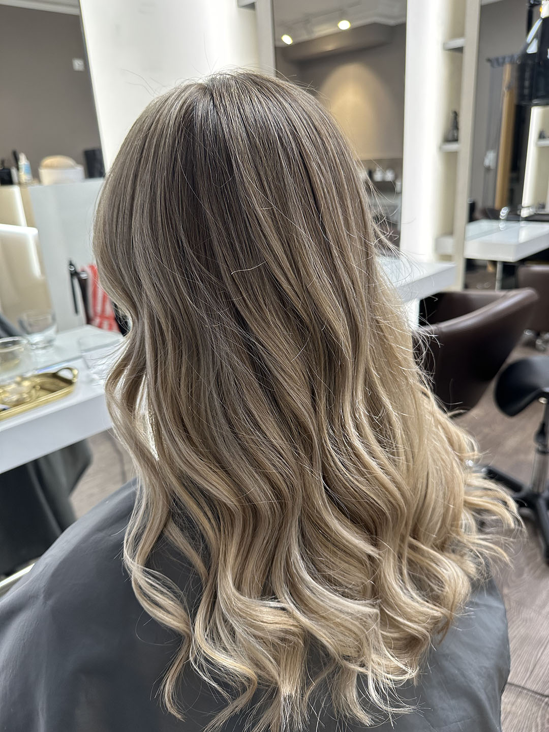 Langes, lockiges blondenes Haar in einem Friseursalon, stilvoll gestaltet und glänzend.