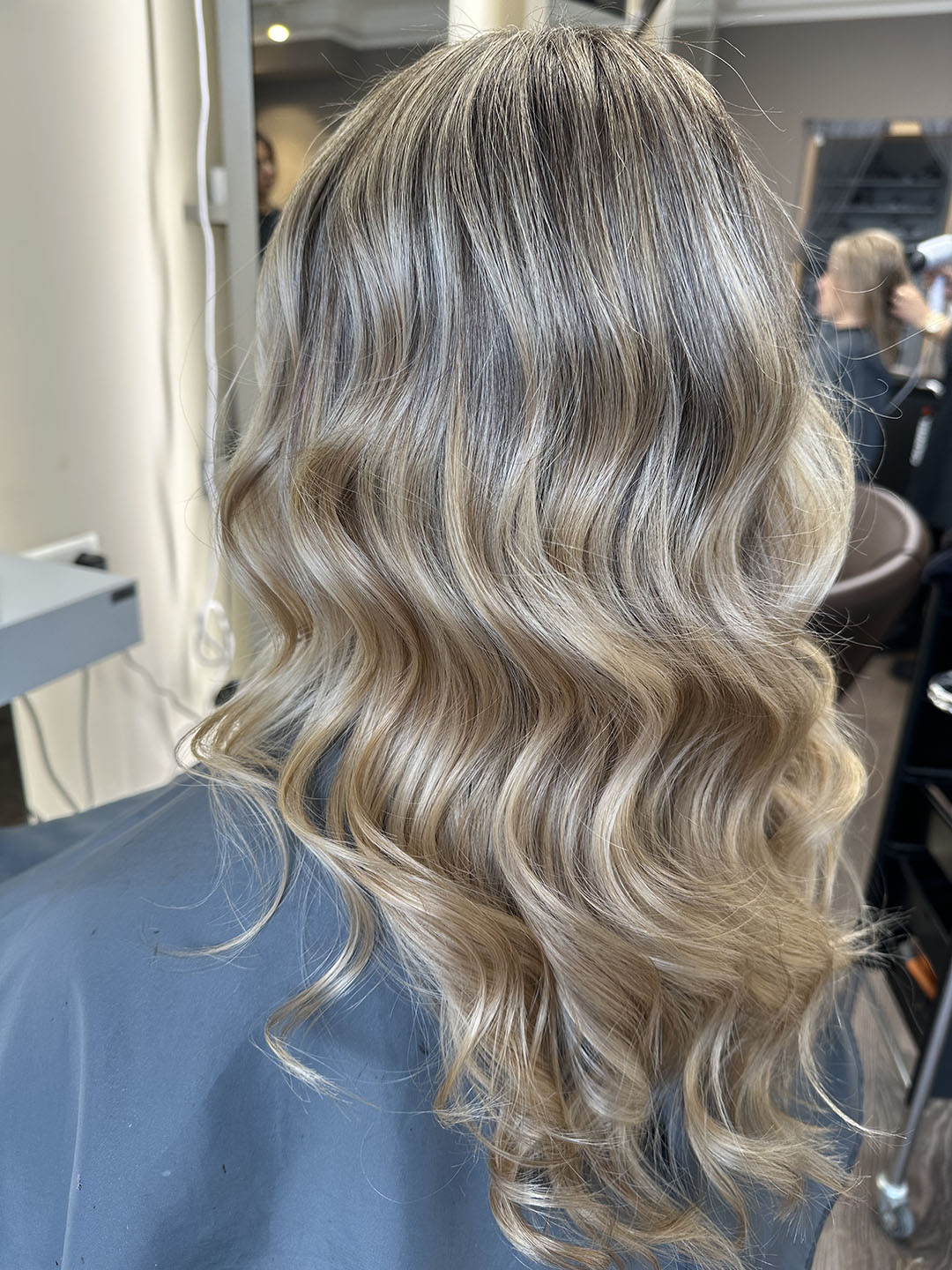 Langes blondes Haar mit sanften Wellen; in einem Friseursalon, elegant und glänzend.