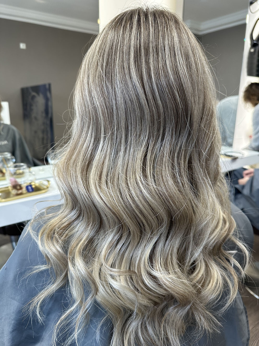 Langes blondes Haar mit sanften Wellen, in einem Salon fotografiert.